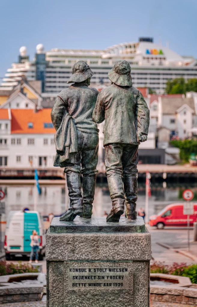 Statue of fisher men in Haugesund with cruise ship in the background